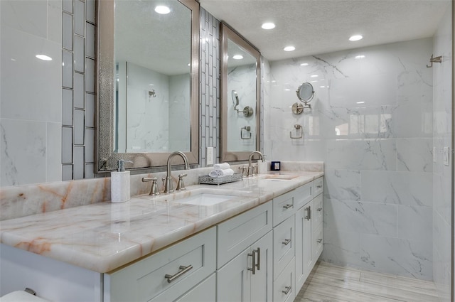 bathroom with a sink, double vanity, recessed lighting, and a textured ceiling