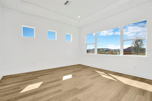 unfurnished room with a raised ceiling, ornamental molding, and light wood-type flooring