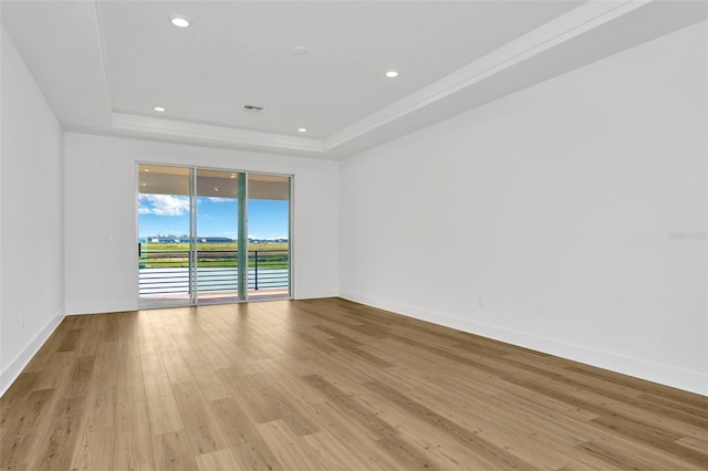 unfurnished room featuring light wood-type flooring and a tray ceiling