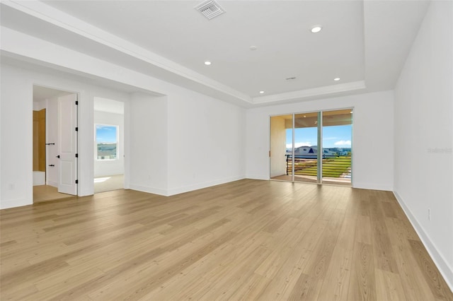 unfurnished room featuring light wood-type flooring and a tray ceiling