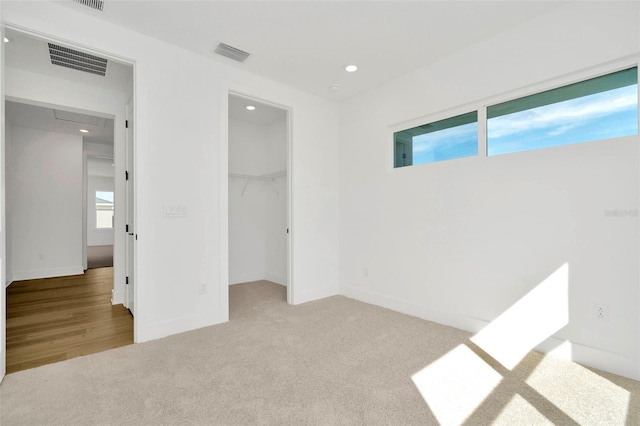 unfurnished bedroom featuring light colored carpet, a spacious closet, and a closet