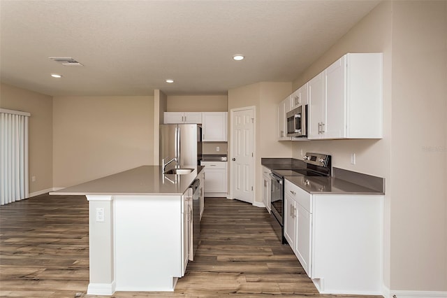 kitchen with white cabinets, dark hardwood / wood-style flooring, an island with sink, and appliances with stainless steel finishes