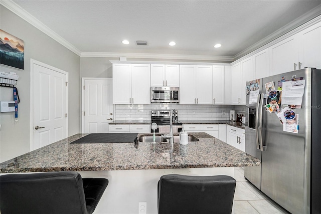 kitchen featuring white cabinets, a kitchen breakfast bar, and appliances with stainless steel finishes