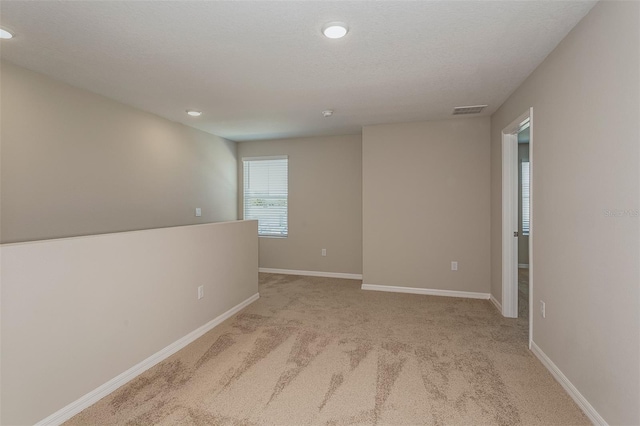 unfurnished room featuring light colored carpet and a textured ceiling