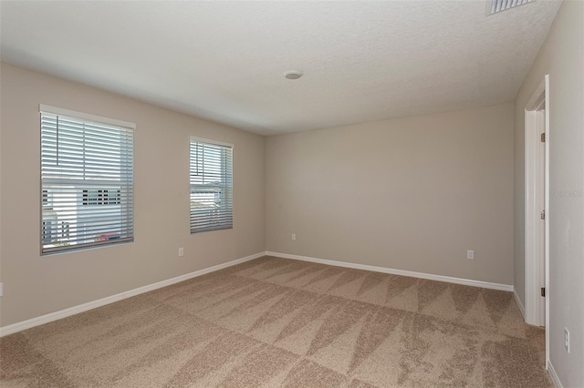 unfurnished room with a textured ceiling and light carpet