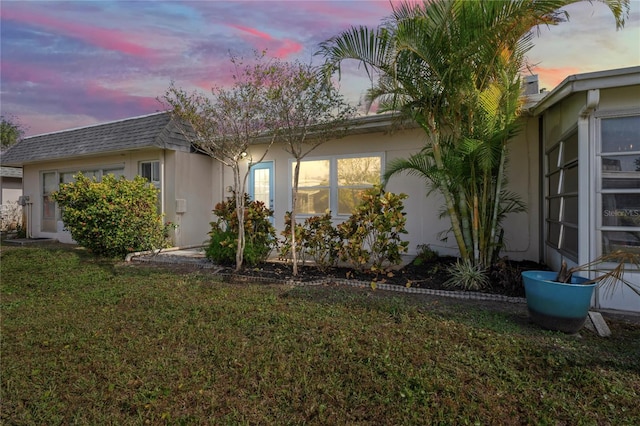 property exterior at dusk with a lawn