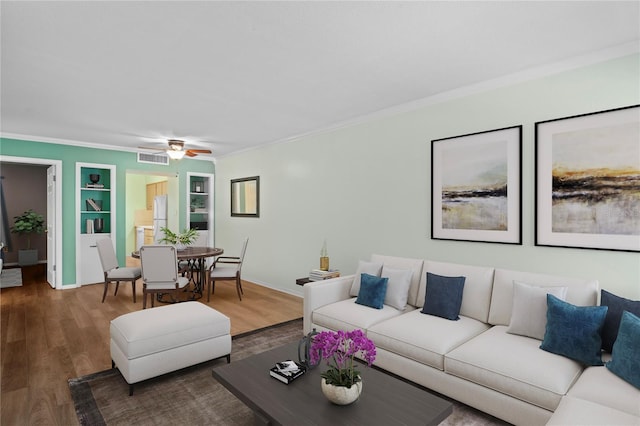 living room featuring ceiling fan, dark wood-type flooring, built in features, and crown molding