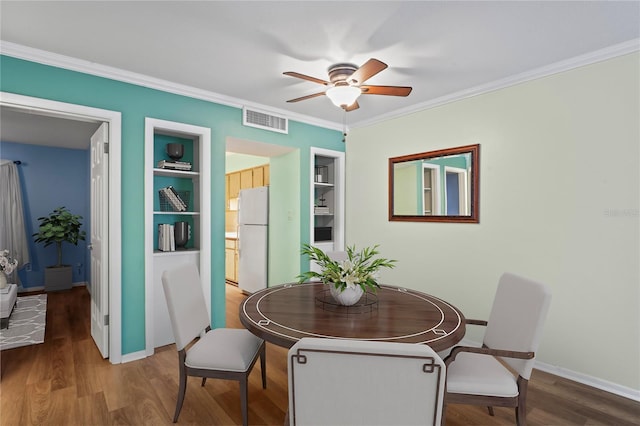 dining space featuring ceiling fan, built in features, ornamental molding, and wood-type flooring