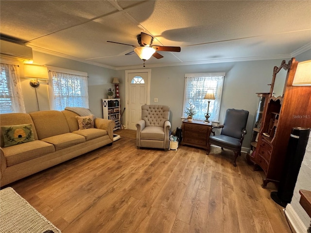 living room featuring ceiling fan, wood-type flooring, a textured ceiling, and ornamental molding