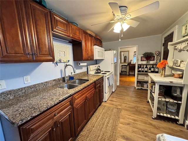 kitchen with ceiling fan, sink, dark stone counters, light hardwood / wood-style floors, and white appliances