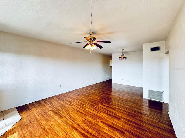 empty room featuring a textured ceiling, ceiling fan, and dark wood-type flooring