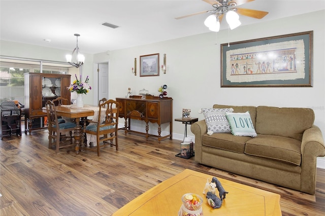 living room with ceiling fan with notable chandelier and wood-type flooring