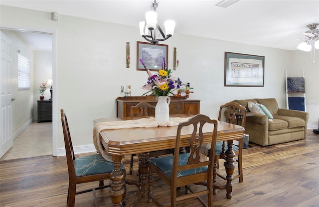 dining space featuring ceiling fan with notable chandelier and wood-type flooring