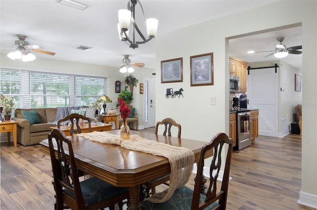 dining area with a chandelier, a barn door, and dark hardwood / wood-style floors