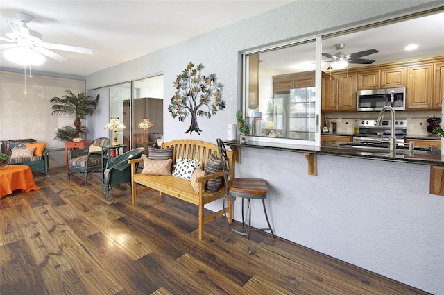 kitchen with decorative backsplash, appliances with stainless steel finishes, a breakfast bar, dark wood-type flooring, and sink