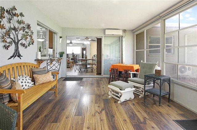 living area featuring ceiling fan, a healthy amount of sunlight, dark wood-type flooring, and a wall unit AC