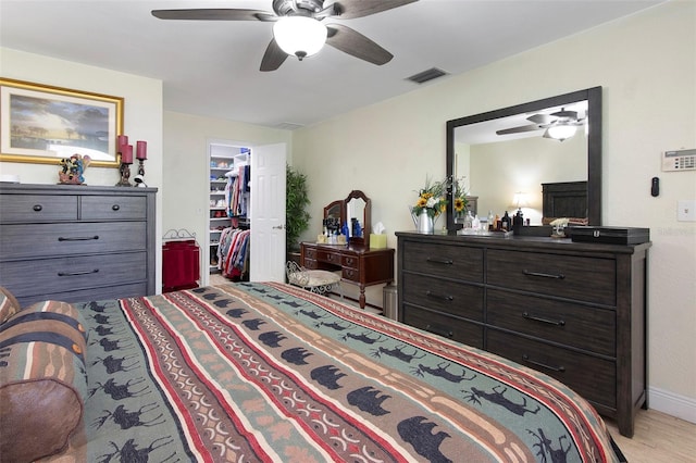 bedroom featuring a walk in closet, ceiling fan, a closet, and light hardwood / wood-style floors