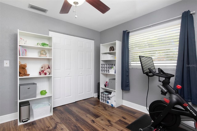 exercise area featuring ceiling fan and dark wood-type flooring