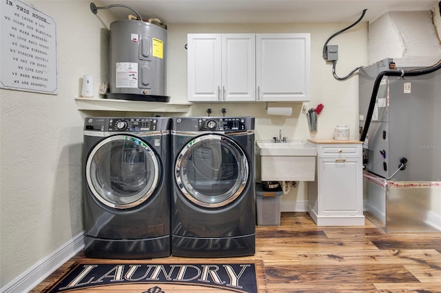 laundry area with water heater, cabinets, light wood-type flooring, and independent washer and dryer