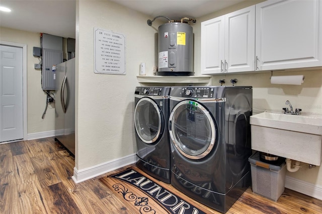 clothes washing area with sink, cabinets, electric water heater, dark hardwood / wood-style floors, and washer and clothes dryer