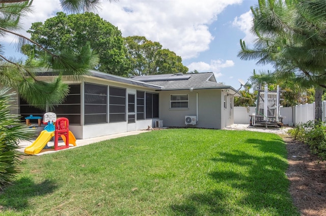 rear view of house featuring a sunroom, a playground, and a yard