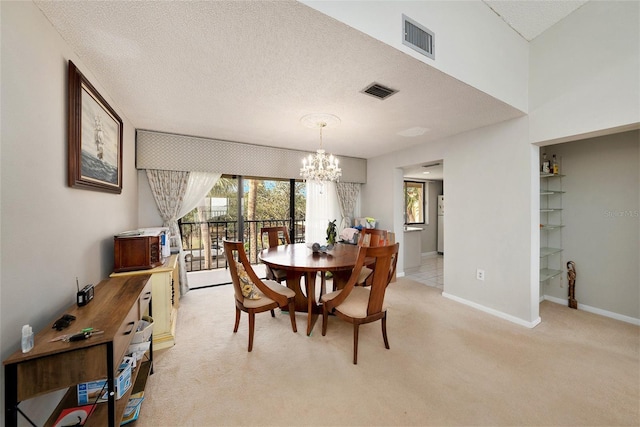 dining area with light colored carpet, a textured ceiling, and a chandelier