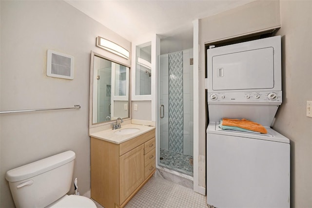 bathroom featuring stacked washer and clothes dryer, toilet, a shower with shower door, vanity, and tile patterned flooring