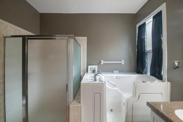 bathroom featuring separate shower and tub, vanity, and a textured ceiling