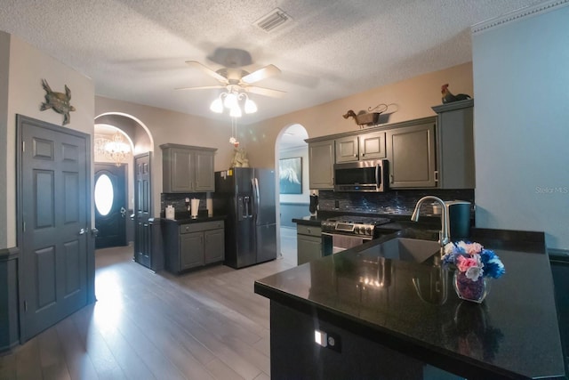 kitchen with gray cabinetry, sink, backsplash, and appliances with stainless steel finishes