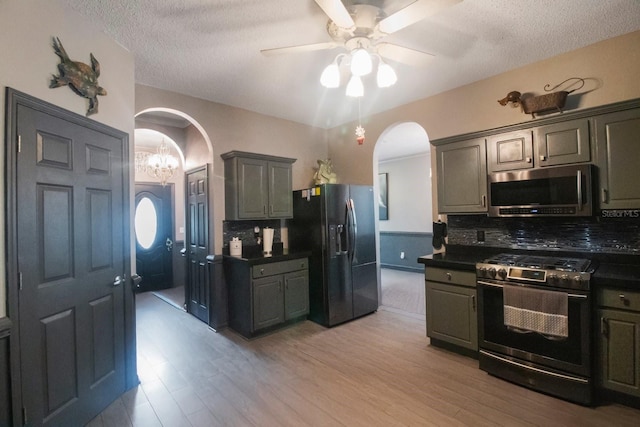 kitchen featuring stainless steel appliances, backsplash, light hardwood / wood-style floors, a textured ceiling, and ceiling fan with notable chandelier