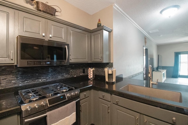 kitchen featuring tasteful backsplash, gray cabinetry, sink, and appliances with stainless steel finishes