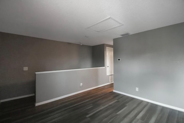 unfurnished room featuring dark wood-type flooring and a textured ceiling