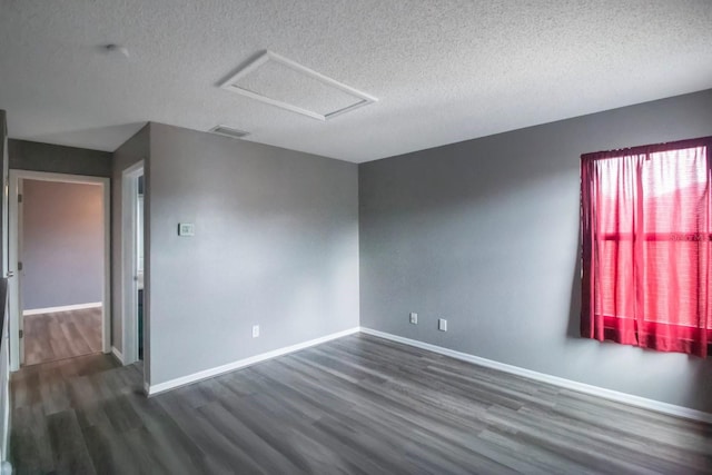 spare room featuring dark hardwood / wood-style flooring and a textured ceiling