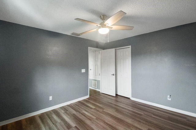 unfurnished bedroom with a textured ceiling, ceiling fan, dark wood-type flooring, and a closet