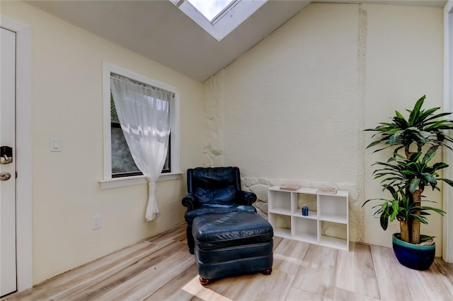 sitting room with lofted ceiling with skylight and wood finished floors