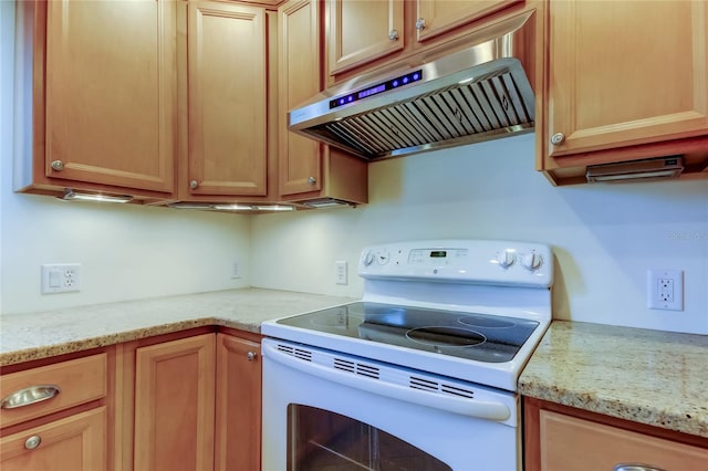 kitchen with light stone countertops, white electric range, and under cabinet range hood