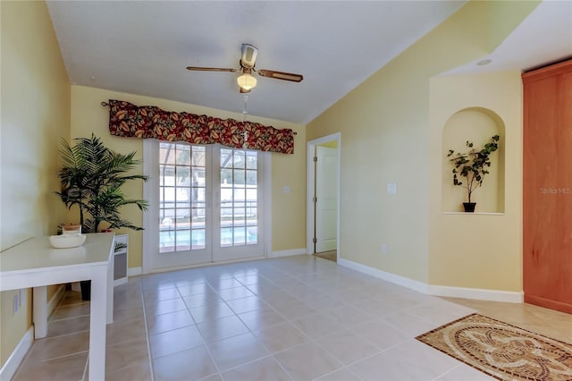 interior space with baseboards, light tile patterned flooring, ceiling fan, vaulted ceiling, and french doors