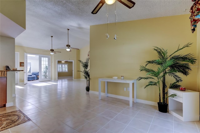 living room featuring a textured ceiling, light tile patterned floors, baseboards, ceiling fan, and vaulted ceiling