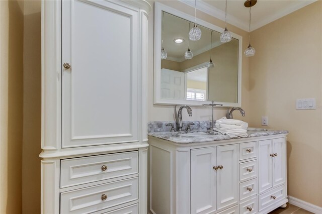 bathroom with vanity, crown molding, and baseboards