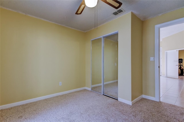 unfurnished bedroom featuring visible vents, baseboards, carpet floors, a closet, and a ceiling fan