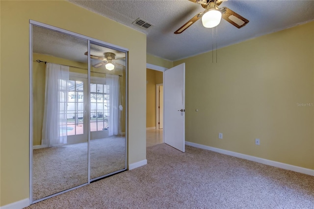 unfurnished bedroom featuring a ceiling fan, baseboards, carpet, visible vents, and a textured ceiling