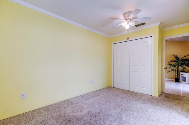 unfurnished bedroom with visible vents, ceiling fan, ornamental molding, a closet, and carpet flooring