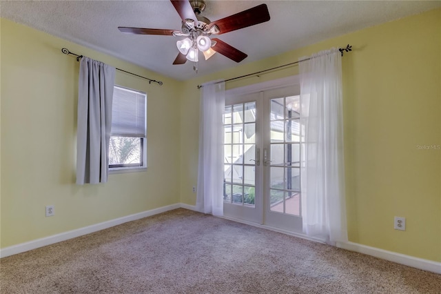 carpeted spare room featuring a ceiling fan, french doors, and baseboards