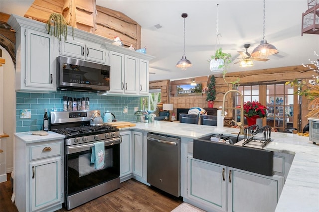 kitchen featuring appliances with stainless steel finishes, dark hardwood / wood-style flooring, tasteful backsplash, white cabinetry, and hanging light fixtures