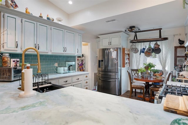 kitchen featuring decorative backsplash, sink, and stainless steel refrigerator with ice dispenser