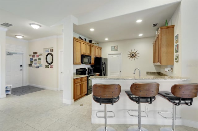 kitchen featuring black appliances, a kitchen breakfast bar, ornamental molding, light stone counters, and kitchen peninsula