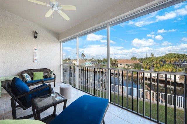 sunroom with ceiling fan and a water view