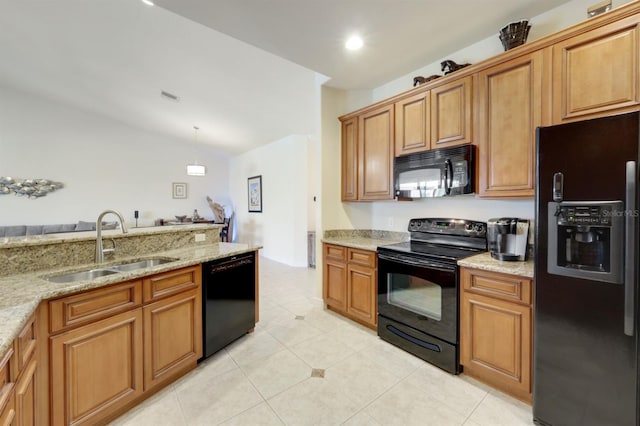 kitchen featuring light stone countertops, sink, black appliances, and decorative light fixtures