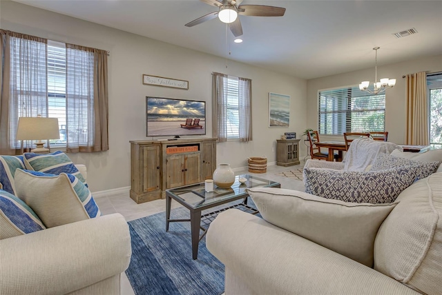 living room featuring a wealth of natural light, light tile patterned flooring, and ceiling fan with notable chandelier