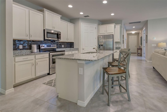 kitchen featuring a kitchen breakfast bar, stainless steel appliances, white cabinetry, and sink